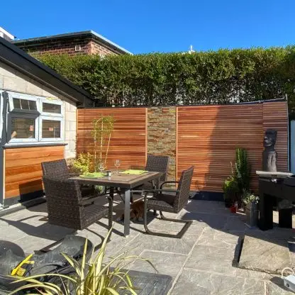 Western red cedar screen slats fixed to a garden wall behind a patio dining set